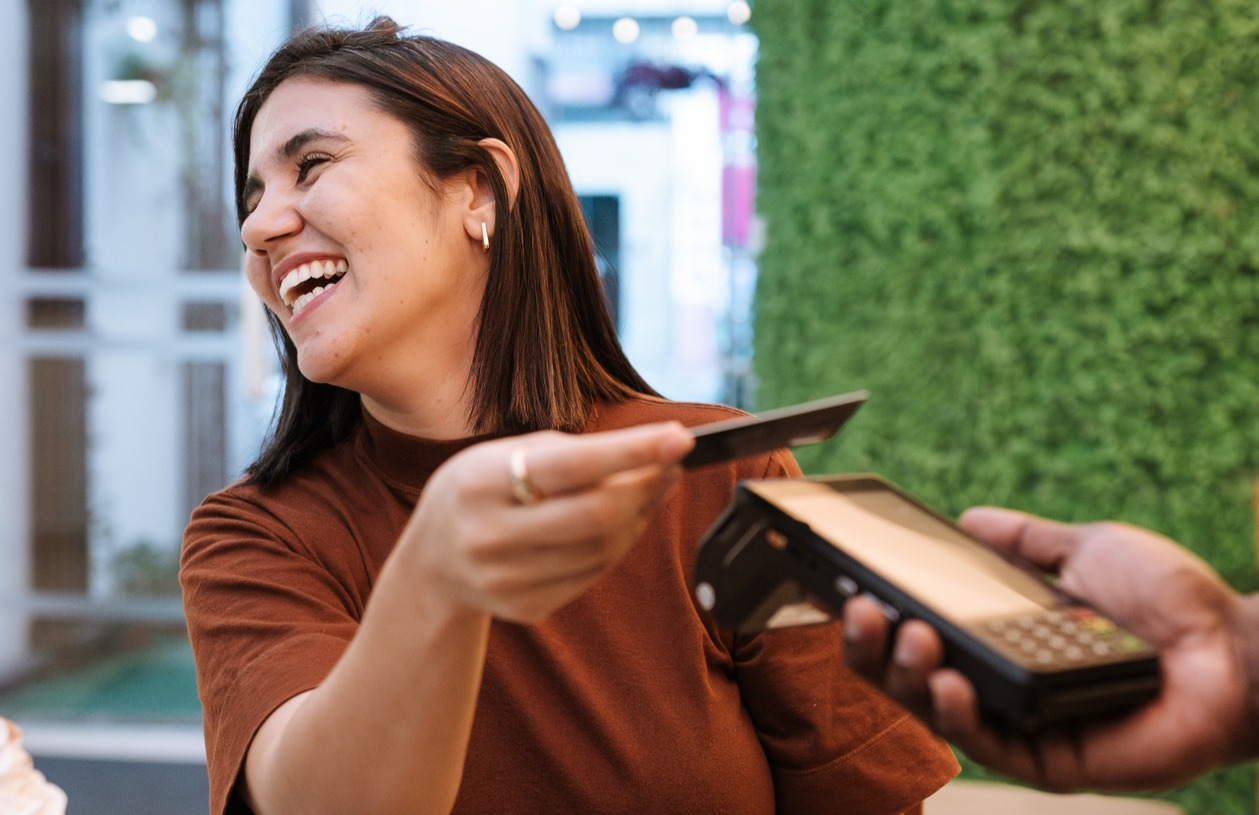 Client comparing cash back and rewards card options with documents on a desk.