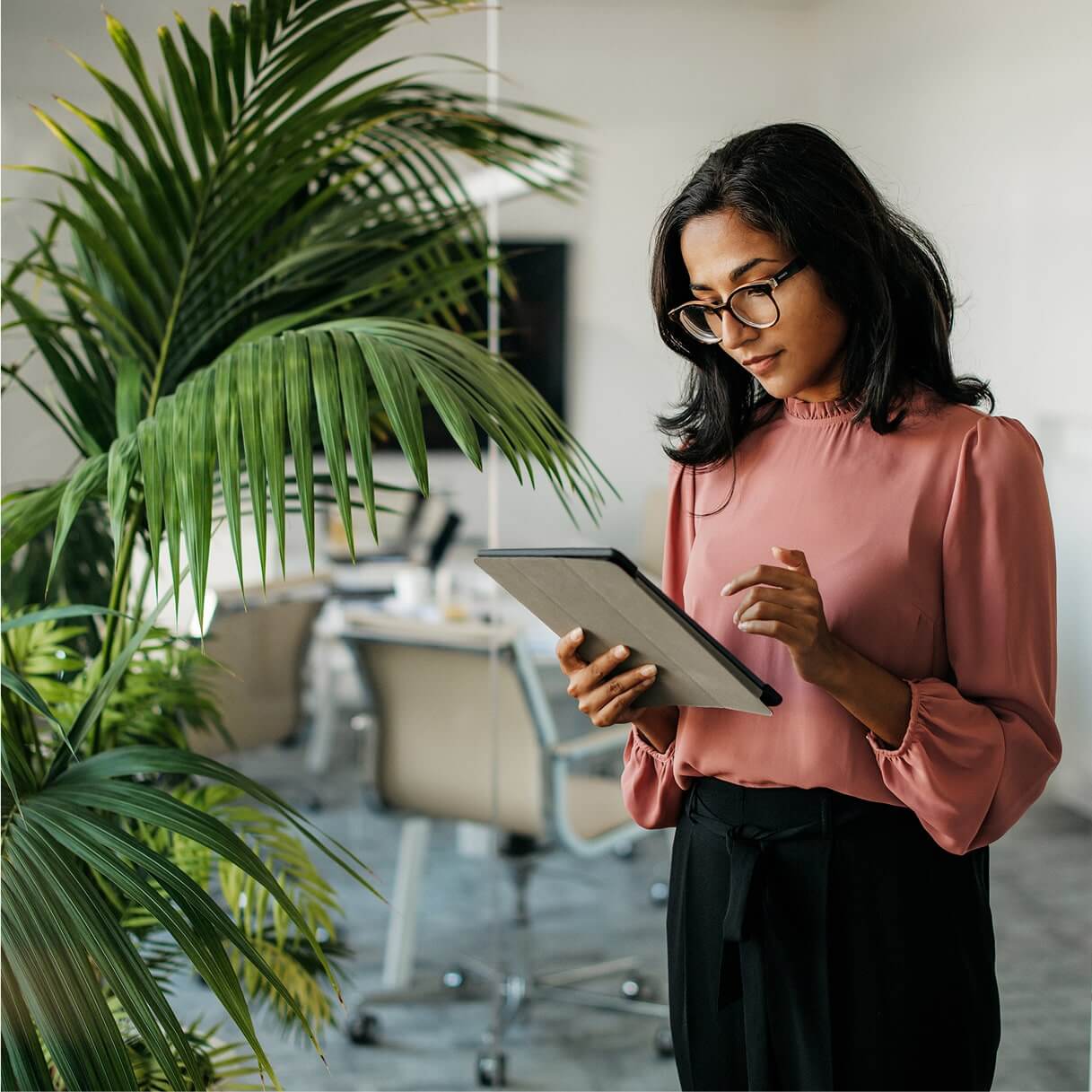 Business professional reviewing account details on a tablet in a bright office.