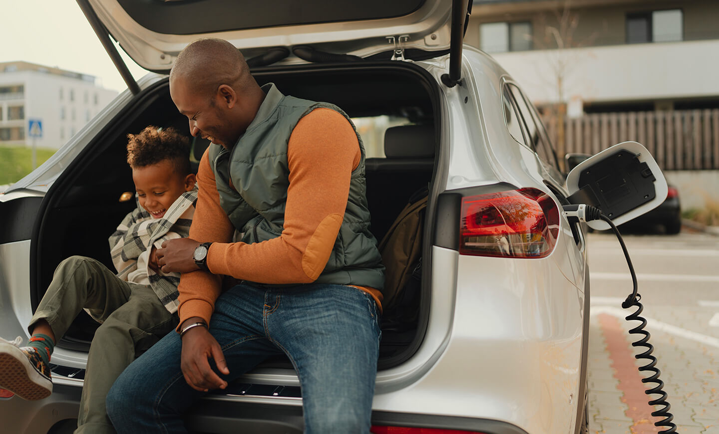 Parent and child at a vehicle trunk, suggesting planning and family finances.